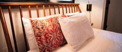 A bed with a wooden headboard, two pillows, and a bedside lamp.