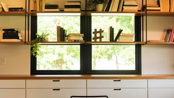 Una habitación con una mesa de comedor, sillas, un ventilador de techo y estantes con libros y objetos decorativos.