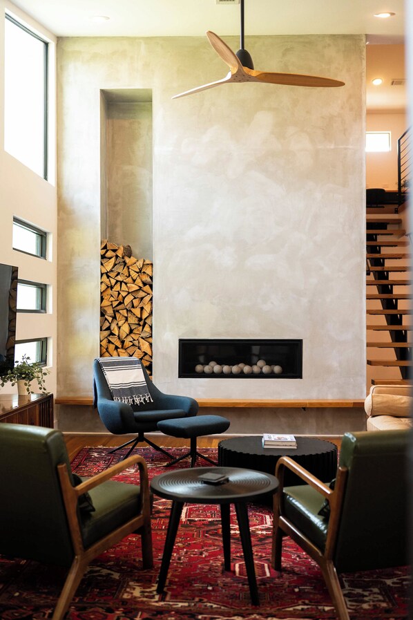 Un saló modern amb una llar de foc, un butac armchair blau, una taula de centre i una catifes amb un disseny decoratiu.