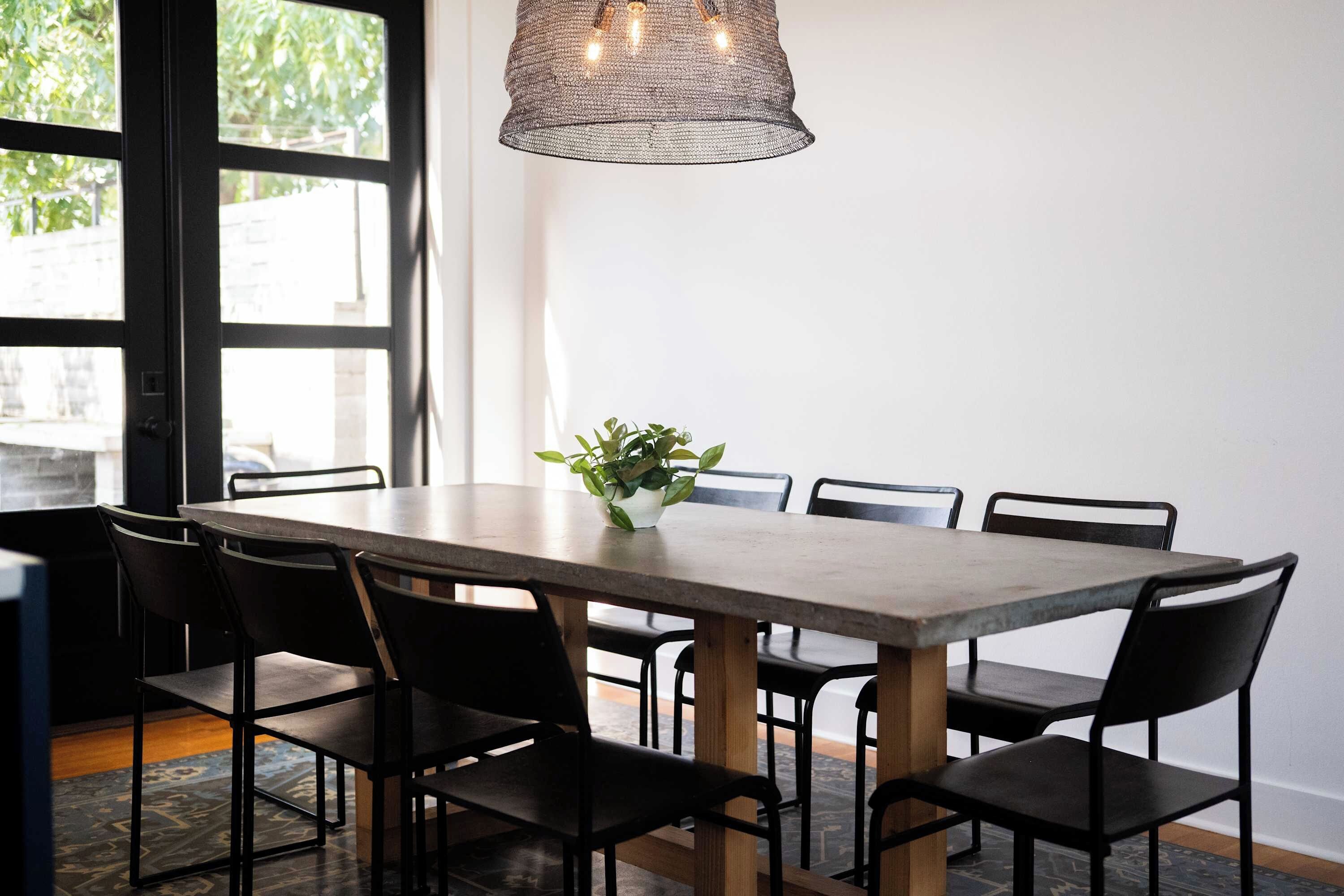 A dining area with a table and chairs, a hanging light fixture, and a potted plant.