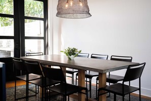 A dining area with a table and chairs, a hanging light fixture, and a potted plant.