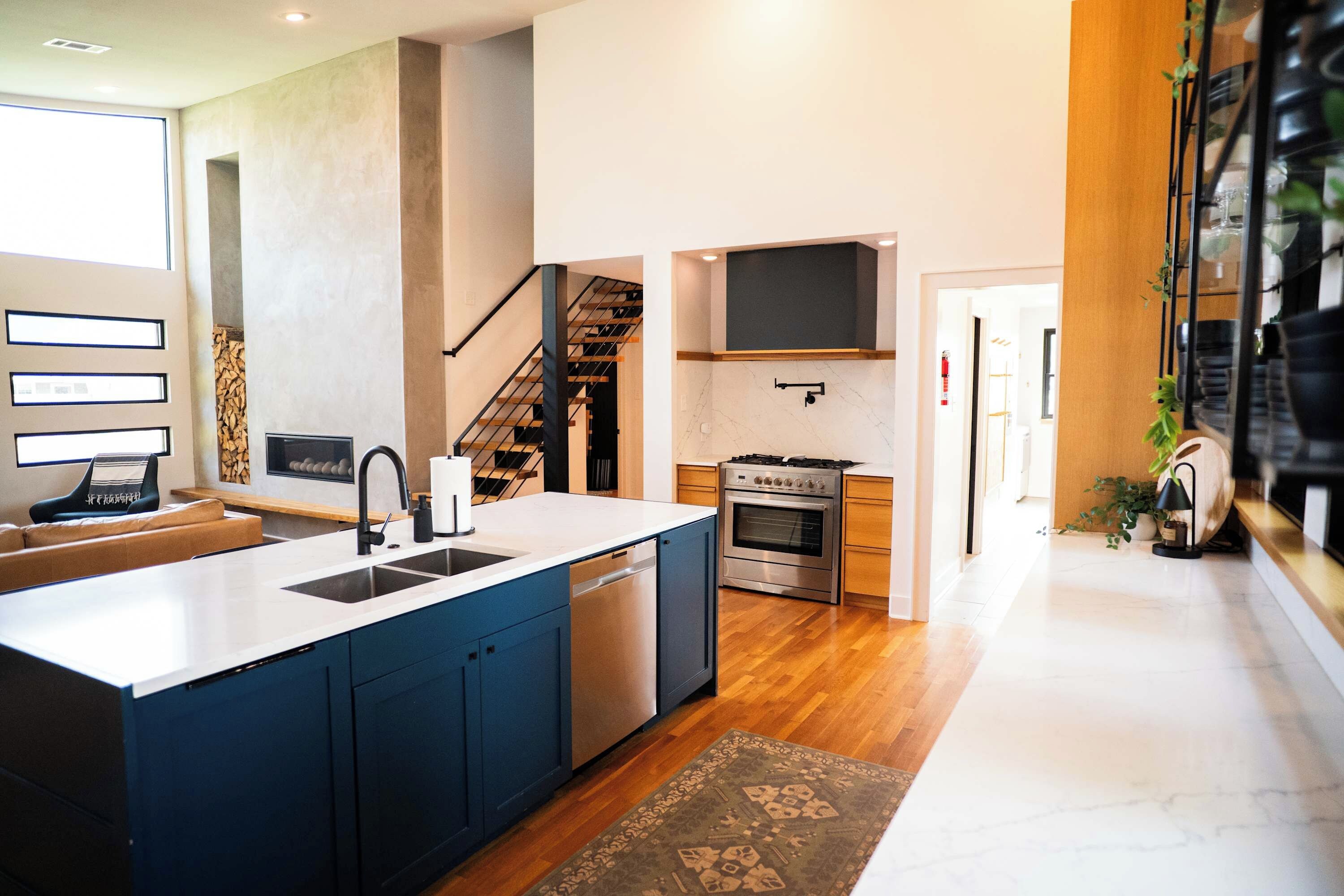 A modern kitchen with a central island, built-in appliances, and a staircase leading to an upper level.