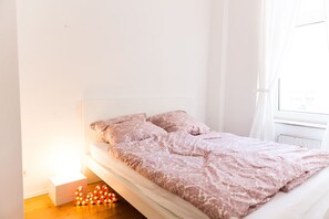 Une chambre à coucher au style minimaliste, avec un lit, une table de chevet et une fenêtre.