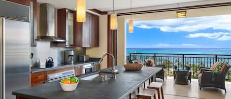 A kitchen with a large island, a coffee maker, and a view of the ocean.
