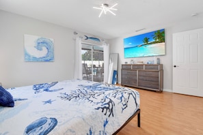Ein Schlafzimmer mit einem Bett, einem Schminktisch, einem Fernseher und einer Tür.