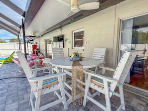 An outdoor patio with a round table and white chairs, a ceiling fan, and a view of the backyard. - Heated Pool w/ Hot Tub • 10 min to Beaches • Pinellas Trail Access (Largo)