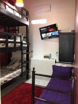 A room with bunk beds, a mounted TV, a cabinet, and a red carpet. - Whale Hill Family Duplex, Units A & B (Puerto Peñasco)