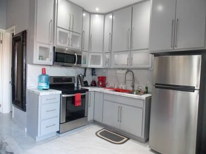 A modern kitchen with stainless steel appliances, white cabinetry, and a marble countertop. - Whale Hill Family Duplex, Units A & B (Puerto Peñasco)