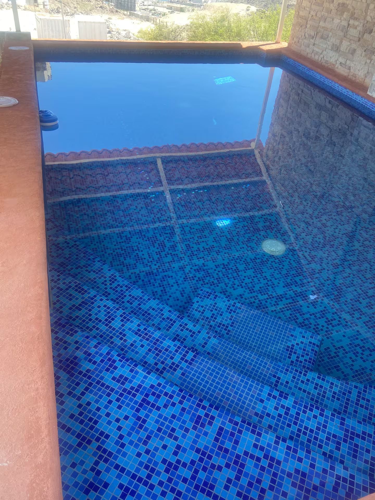 Una piscina con suelo de baldosas y vistas de los alrededores.