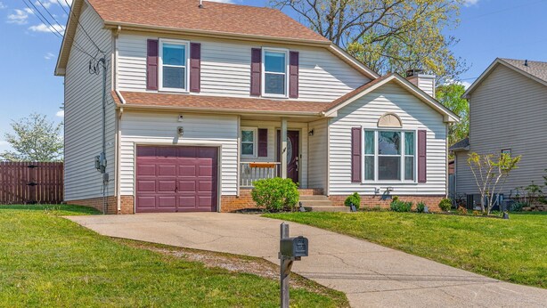 A two-story house with a front garage, a small porch, and a well-maintained lawn. - Relax & Recharge  Cozy 2BR Near Fort Campbell (Clarksville)