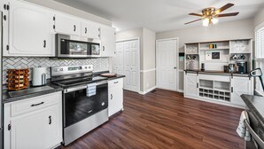 A modern kitchen with white cabinetry, stainless steel appliances, and a wooden floor. - Relax & Recharge  Cozy 2BR Near Fort Campbell (Clarksville)
