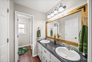 A bathroom with two sinks, a large mirror, and a shower.