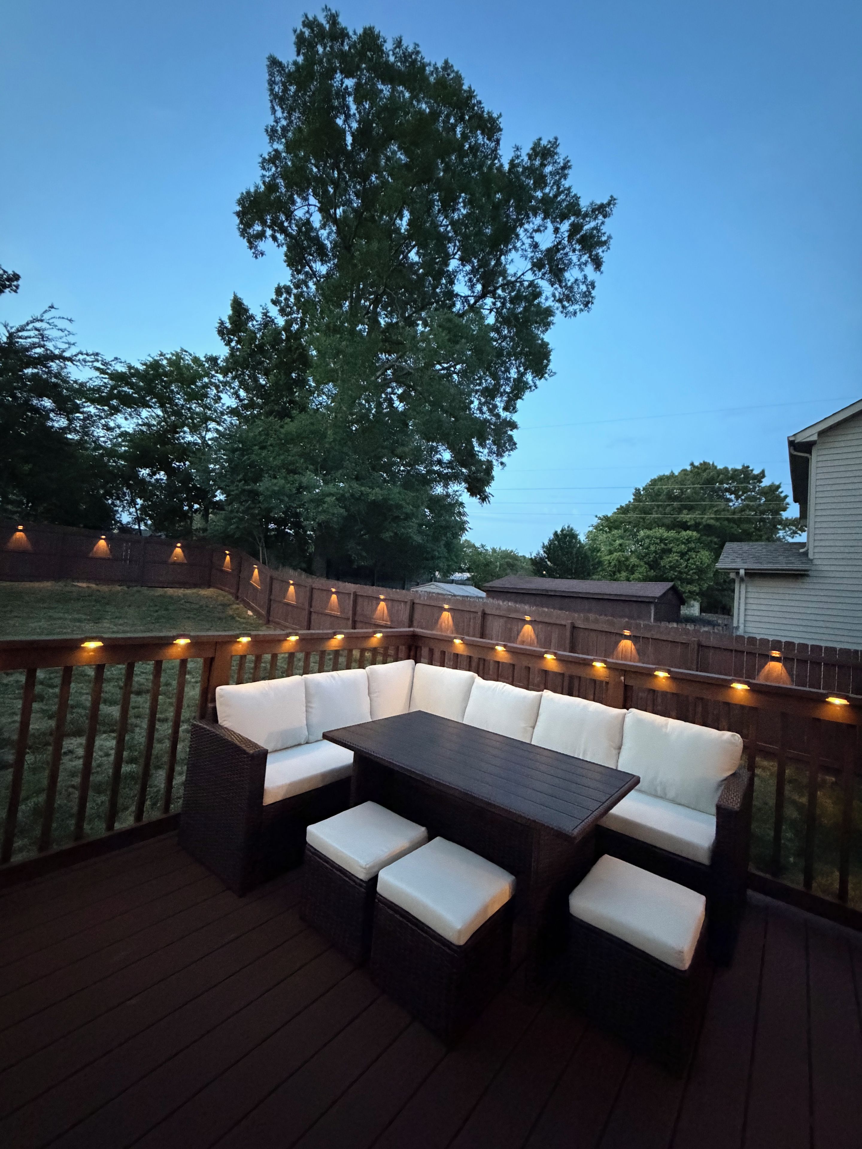 An outdoor deck with a dark wood table and white cushioned seating.