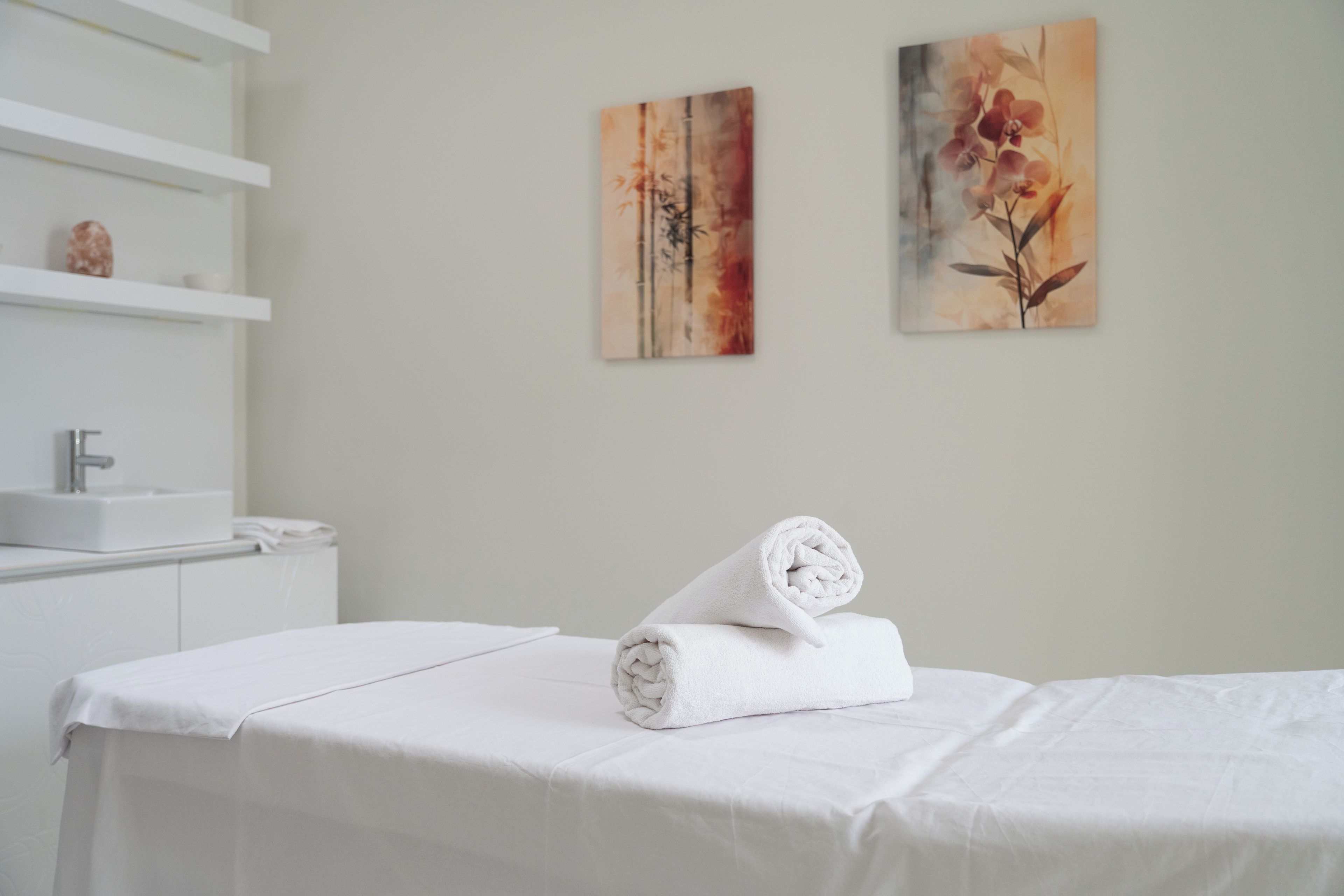 Una habitación de hotel con una cama bien hecha, un lavabo blanco y dos cuadros colgados en la pared.