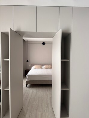 A bedroom with a bed, a nightstand, and a hanging light fixture. - Zahir Rooms & wellness (Trapani)
