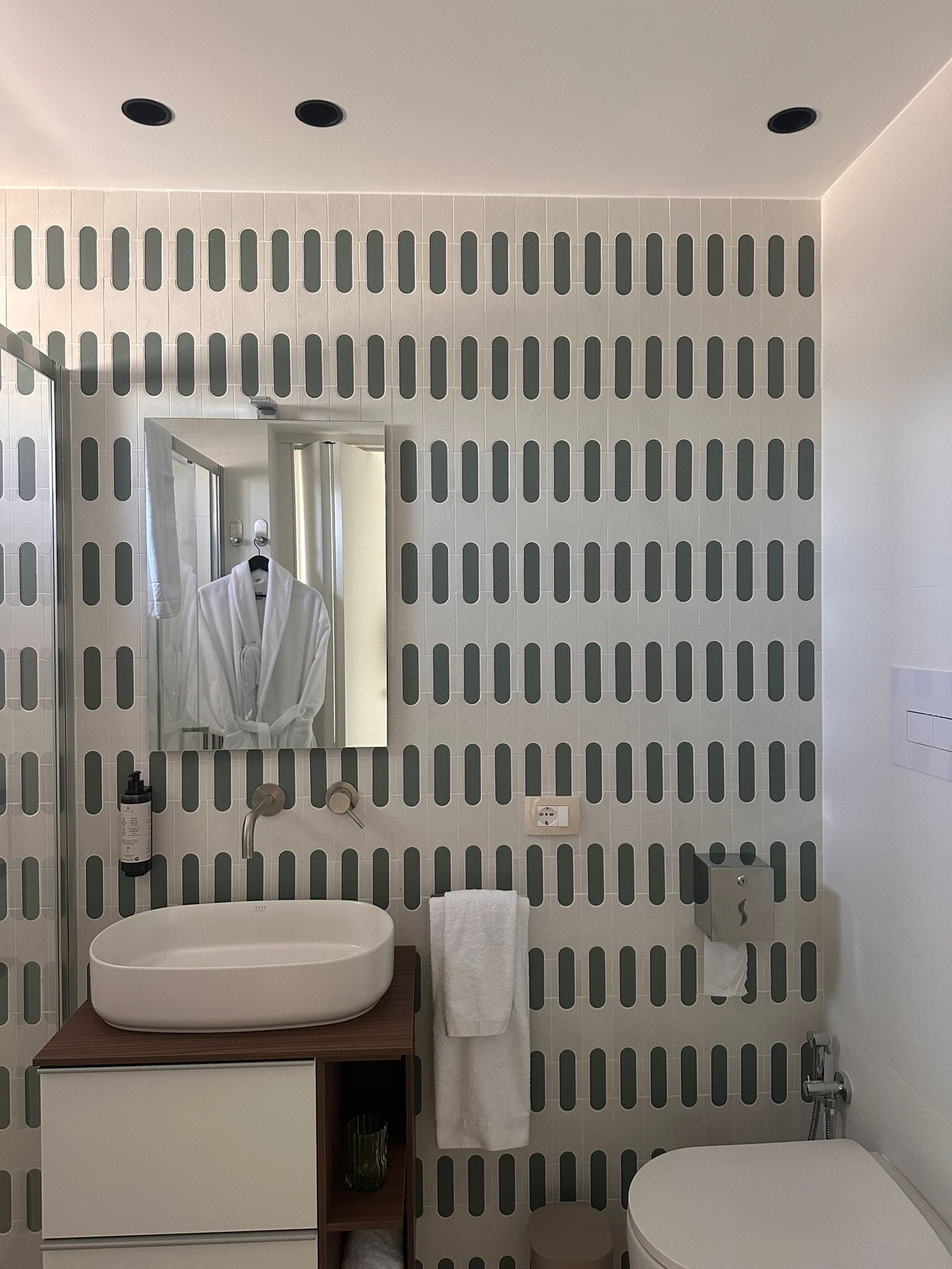 Ein Badezimmer mit Waschbecken, Spiegel, Handtuchhalter und Toilette.