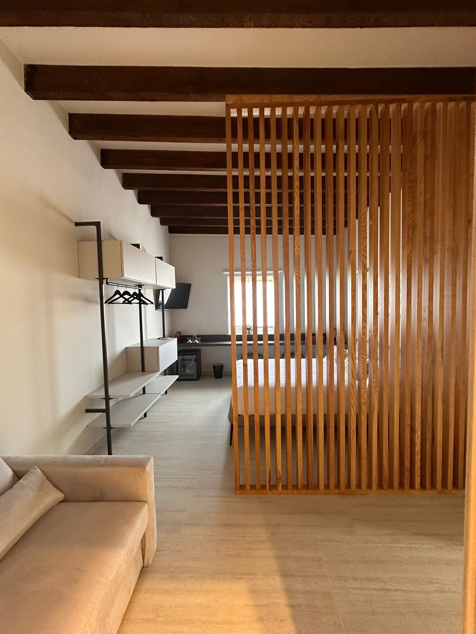 Ein modernes Hotelzimmer mit einer Holzwand, einer Sitzecke, einem Schreibtisch mit Computer und einem Bett.