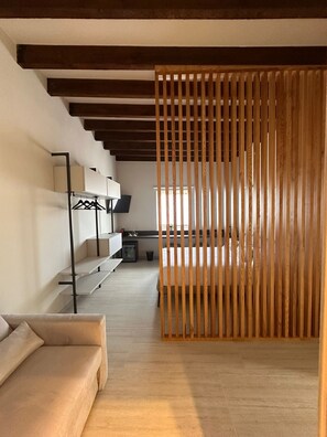 A modern hotel room with a wooden partition, a sofa, a desk with a computer, and a bed. - Zahir Rooms & wellness (Trapani)