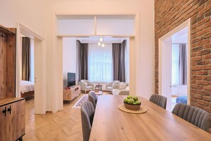 Ein modernes Wohnzimmer mit einem Holzespeisetisch, grauen Sofas und einer Ziegelwand als Blickfang.