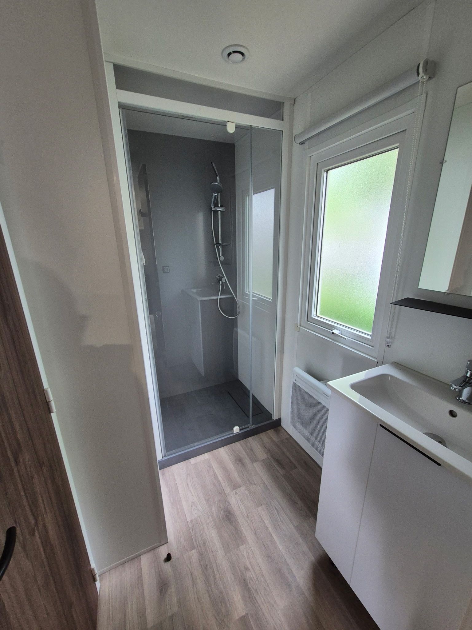 A modern bathroom with a shower, a sink, and a window.