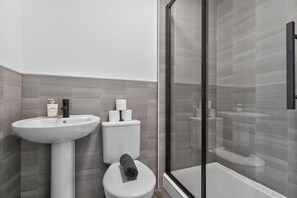A modern bathroom with a white sink, toilet, and shower area. - Stylish 2Bed, 2Bath Near Failsworth Manchester (Failsworth)