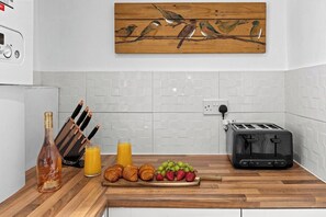 A kitchen with a wooden countertop, a toaster, a bottle of liquor, and a fruit platter. - Spacious 3BR Home | 15 Mins to Manchester (Swinton)