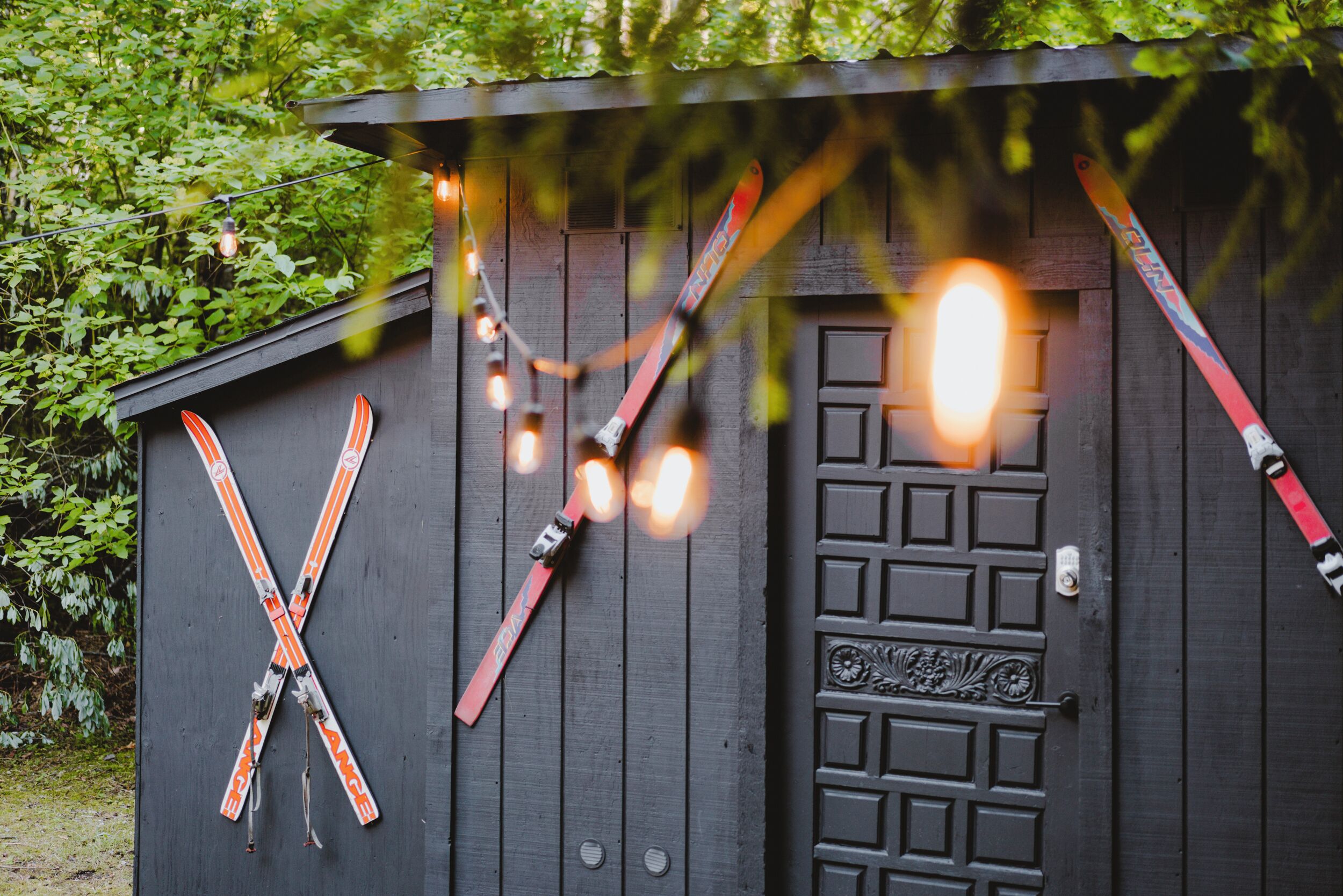A wooden shed with skis hanging on the side and a door with a decorative panel.