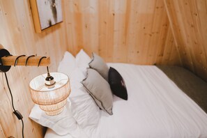 A wooden room with a bed, pillows, a hanging lamp, and a wall-mounted picture. - Tye Hideout (Skykomish)