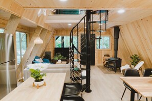 A modern loft-style interior with a wooden interior, a black spiral staircase, a dining area, and a living space with a fireplace. - Tye Hideout (Skykomish)