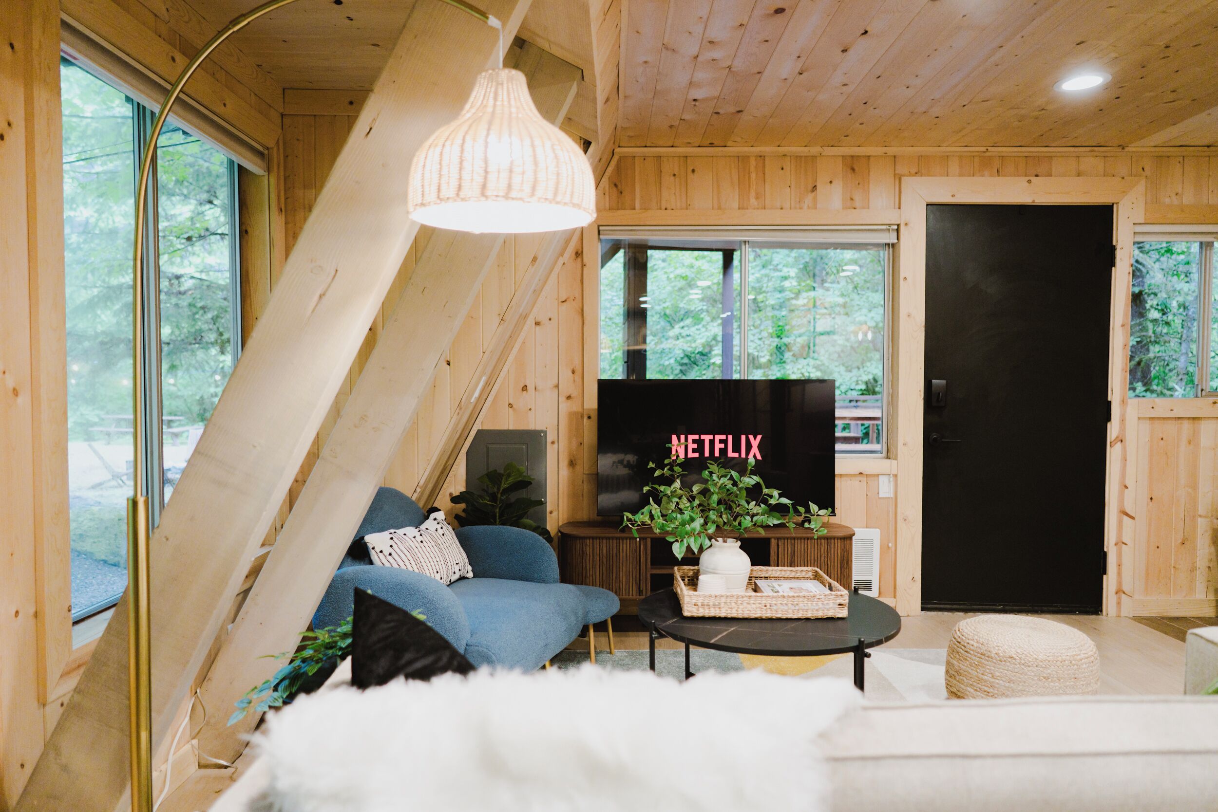 Ein gemütliches Wohnzimmer mit schräg verlaufender Decke, einer Couch, einem Couchtisch und einem Fernseher.