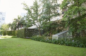Ein Wohnhaus mit gepflegtem Garten, einem Gewächshaus und einer Hecke.