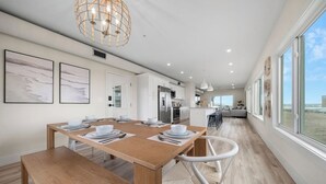 Una cocina moderna con armarios blancos, una mesa de comedor de madera lista para cuatro comensales y un amplio ventanal con vistas panorámicas.