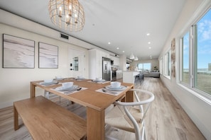 Een moderne keuken met witte kasten, een houten eettafel gedekt voor vier personen en een groot raam met uitzicht op een prachtig landschap.