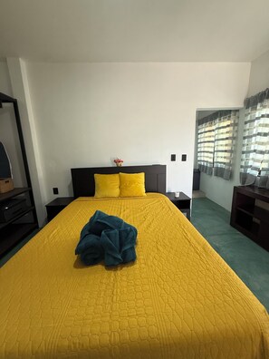 Ein Hotelzimmer mit einem großen Bett, einem Nachttisch und einem Fenster mit Vorhängen.