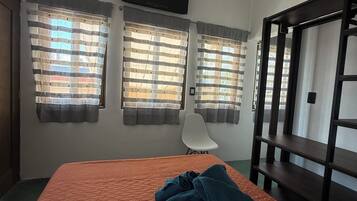 Una habitación con una cama, una silla y un televisor montado en la pared.