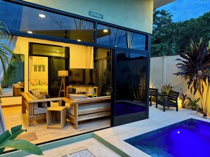 A modern outdoor living area with a pool, seating, and a large glass door. - Awesome 4-bedroom estate with AC in charming Puerto Viejo (Puerto Viejo)