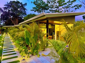 A modern building with a covered outdoor area, surrounded by lush greenery and a pathway. - Awesome 4-bedroom estate with AC in charming Puerto Viejo (Puerto Viejo)