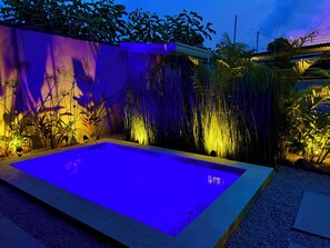 A swimming pool with a geometric design, surrounded by lush vegetation and illuminated by ambient lighting. - Awesome 4-bedroom estate with AC in charming Puerto Viejo (Puerto Viejo)