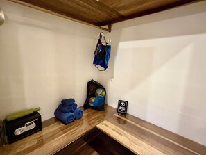 Um quarto com um banco de madeira, uma caixa preta com um objeto verde e uma placa que diz 'POR FAVOR, NÃO SE SENTE'.