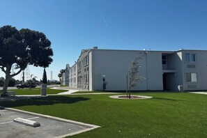 Ein modernes Gebäude mit Flachdach, einer kleinen Pflanze in der Mitte und blauem Himmel.