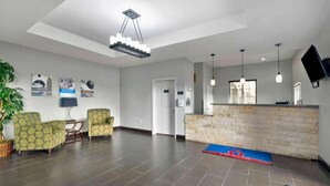 Eine Hotlellobby mit einer Rezeption, einer Sitzecke und einer großen Pflanze.