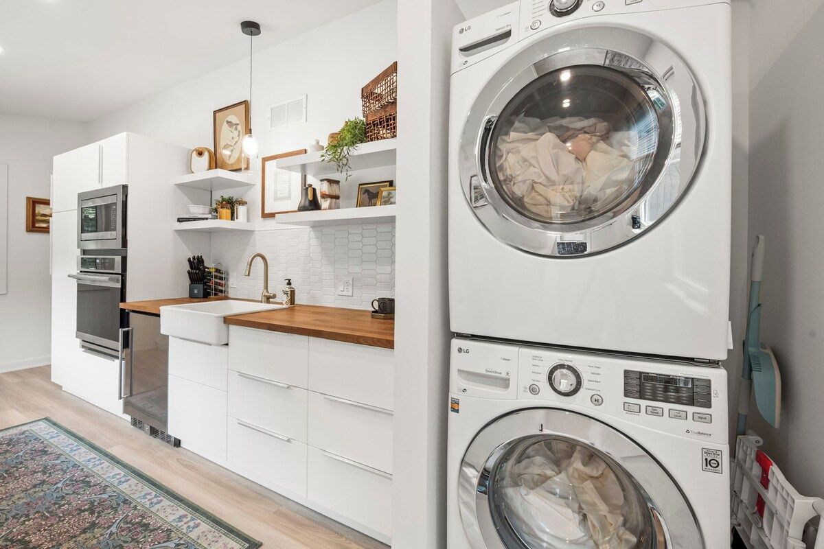 Een moderne keuken met witte kasten, een ingebouwde oven en een wasmachine.