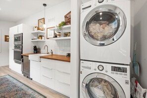 Een moderne keuken met witte kasten, een ingebouwde oven en een wasmachine.