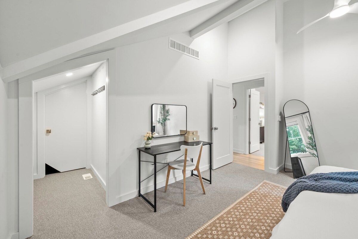 Een moderne slaapkamer met een bed, een bureau en een spiegel.