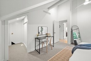 Een moderne slaapkamer met een bed, een bureau en een spiegel.