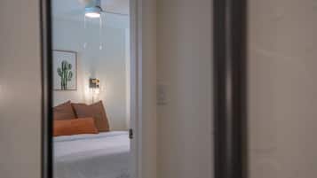 A bedroom with a bed, pillows, a wall-mounted light fixture, and a ceiling fan.