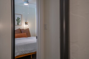 A bedroom with a bed, pillows, a wall-mounted light fixture, and a ceiling fan. - Presidio Flat at Hoff & Co | Downtown Tucson (Tucson)