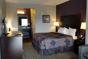 A hotel room with a bed, bedside lamps, a desk with a lamp, a mirror, and a framed picture on the wall. - Functional Studio Offers Extended Stay Comfort Near Downtown Beeville (Beeville)