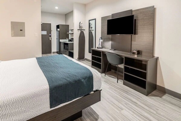 Ein Hotelzimmer mit Bett, Schreibtisch, Sessel, Fernseher und Kleiderschrank.