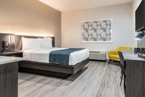 Ein modernes Hotelzimmer mit Bett, Nachttisch, Lampe, Klimaanlage und einem gelben Sessel.